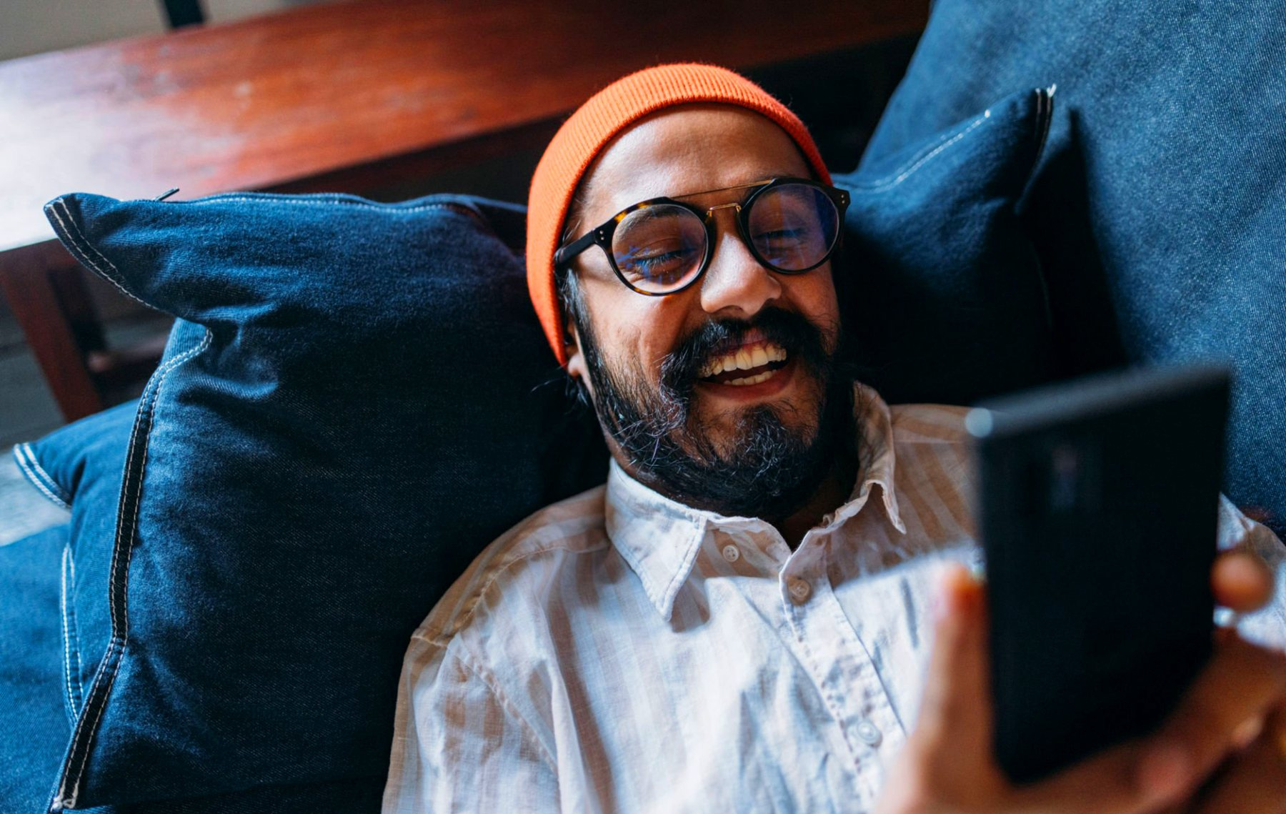 A man reading a message on his phone, relaxed at home